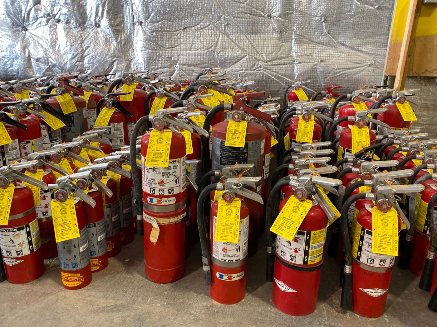 Rows of portable fire extinguishers and service tags in All-Safe’s shop