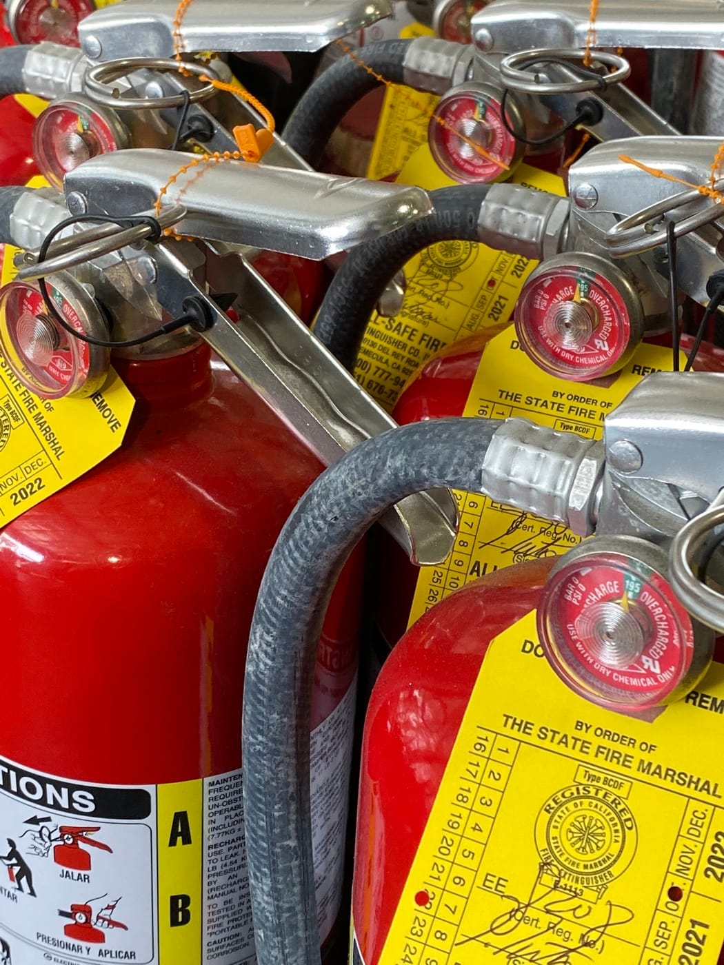 Close-up of multiple extinguisher gauges, handles, hoses, and service tags