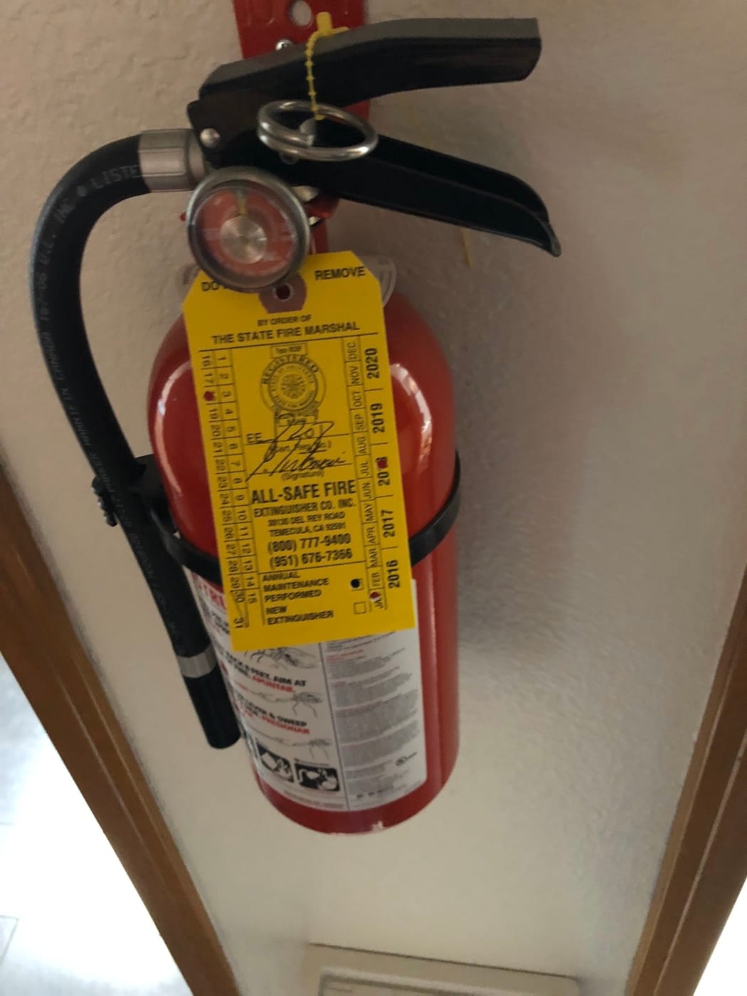 Wall-mounted portable extinguisher beside a doorway, from All-Safe’s photo archive