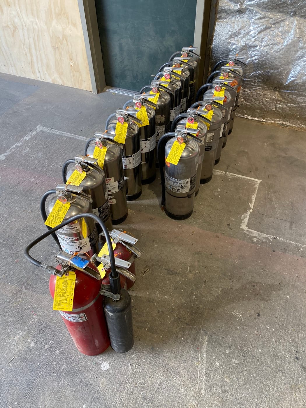 A line of red and stainless-steel portable extinguishers in All-Safe’s shop