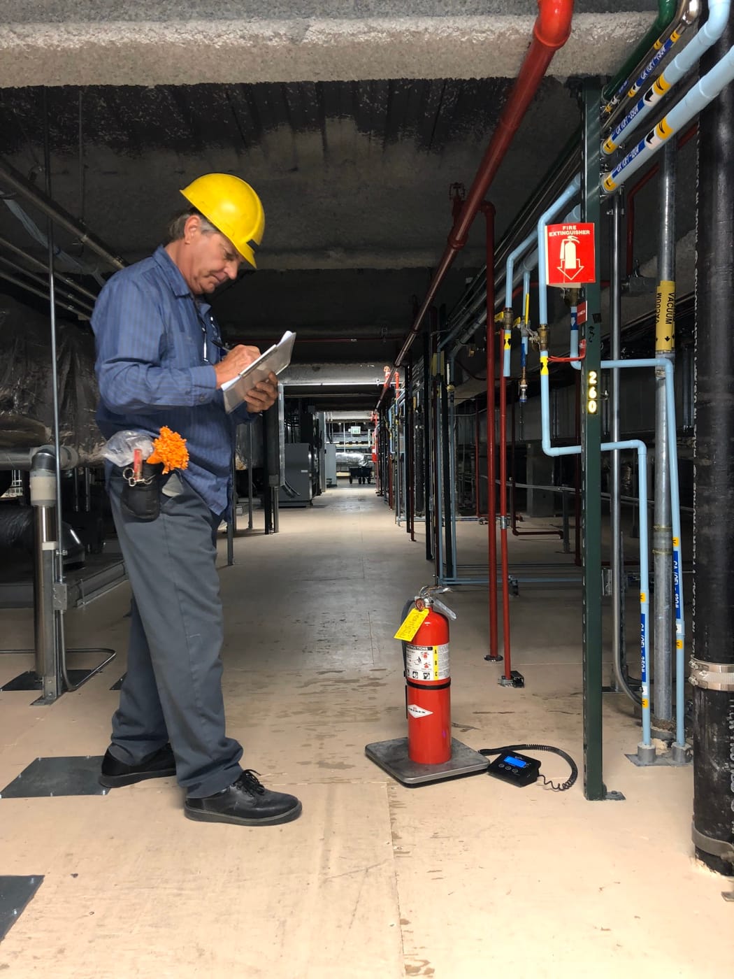 An All-Safe technician standing with a clipboard during an on-site equipment inspection