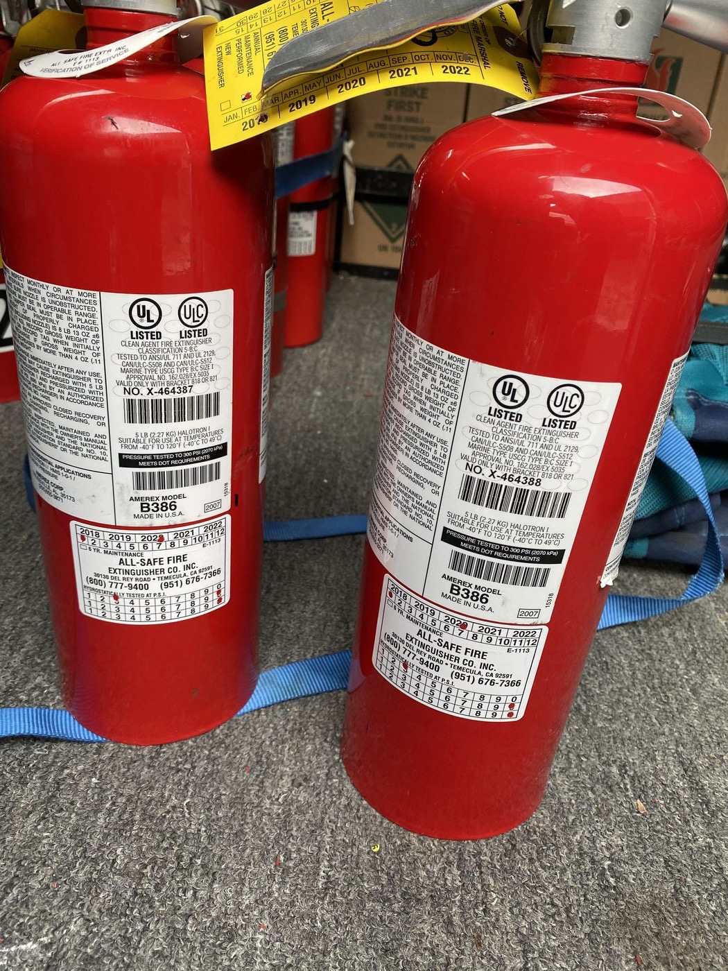 Close-up of two portable extinguishers with equipment labels and All-Safe service stickers