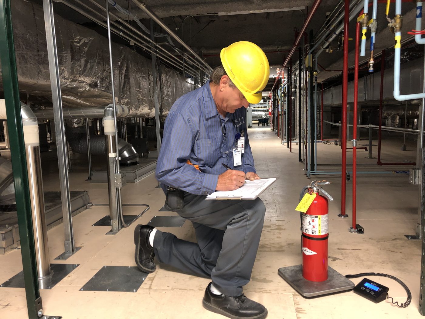 An All-Safe technician documenting extinguisher service on site