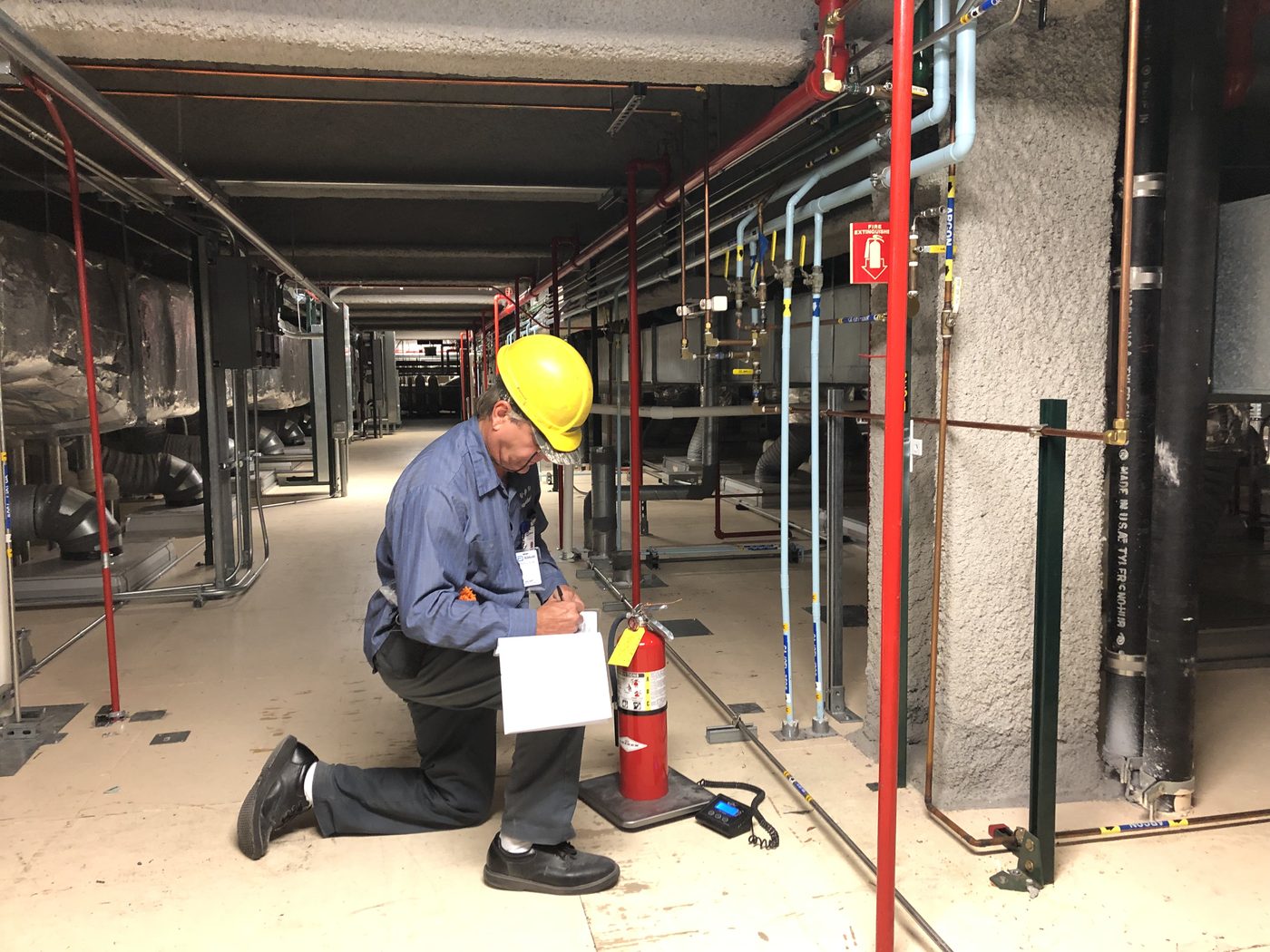 An All-Safe technician documenting an extinguisher inspection in the field